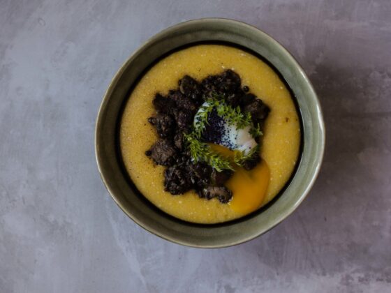 Tabletop image of mushrooms, lentils, cheesy polenta and poached egg on a grey background